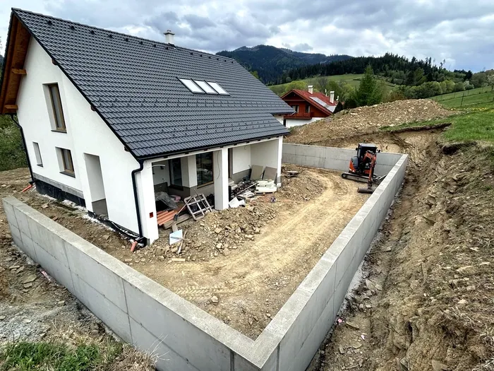 Dokončený betónový oporný múr okolo rodinného domu na svahovitom pozemku