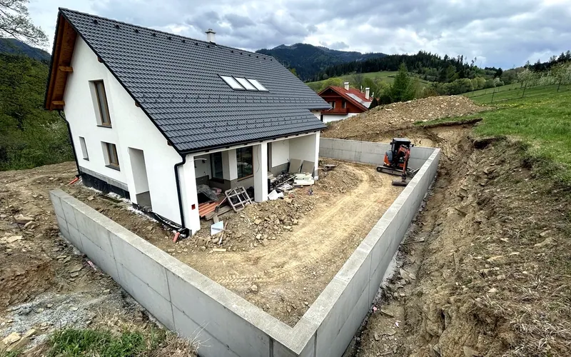 Dokončený betónový oporný múr okolo rodinného domu na svahovitom pozemku